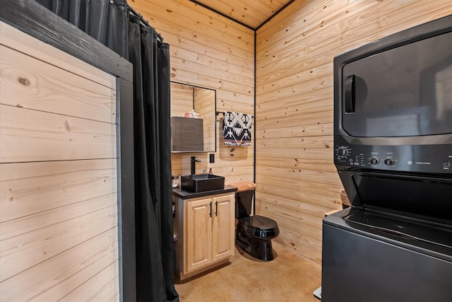 interior space featuring stacked washer / dryer, light brown cabinets, and wooden walls