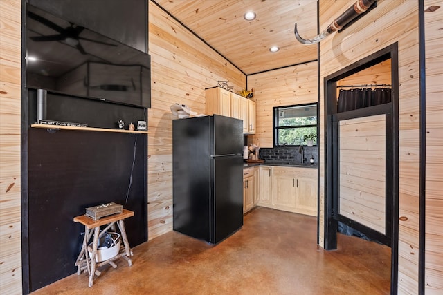 kitchen with wooden walls, wooden ceiling, sink, light brown cabinets, and black refrigerator