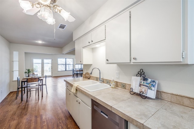 kitchen with stainless steel dishwasher, tile counters, sink, and white cabinets