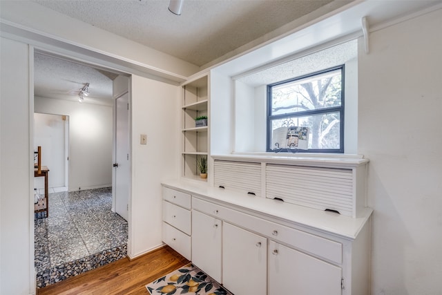 interior space with white cabinetry, light hardwood / wood-style flooring, and a textured ceiling