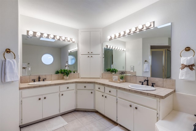 bathroom with tile patterned flooring, vanity, and walk in shower