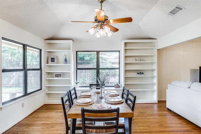 dining area with lofted ceiling, a textured ceiling, ceiling fan, and light wood-type flooring