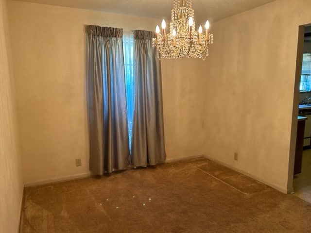 unfurnished room featuring a notable chandelier and carpet floors