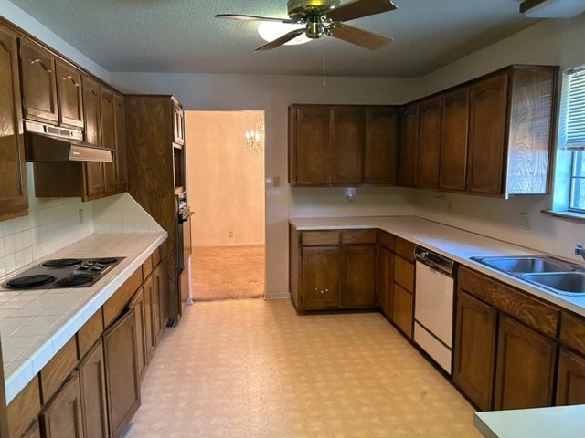 kitchen with dark brown cabinets, stainless steel appliances, tile counters, sink, and ceiling fan