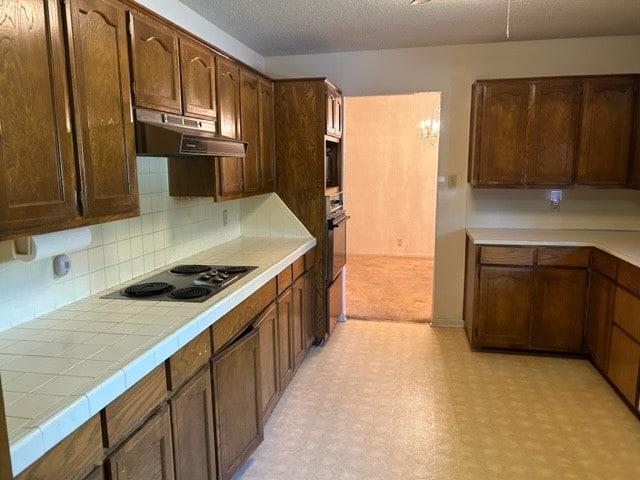 kitchen with oven, tile countertops, electric cooktop, and decorative backsplash