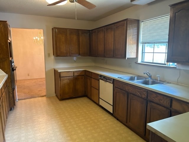 kitchen featuring ceiling fan with notable chandelier, stainless steel dishwasher, and sink