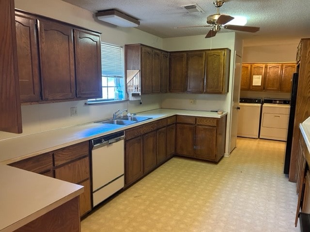 kitchen with a textured ceiling, dishwasher, washer and clothes dryer, sink, and ceiling fan