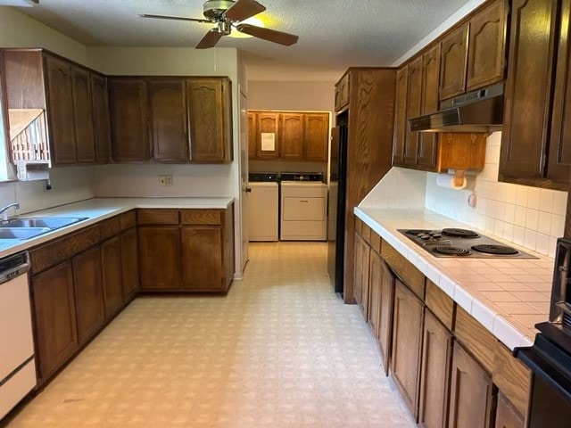 kitchen with washer and dryer, stainless steel dishwasher, sink, electric stovetop, and ceiling fan