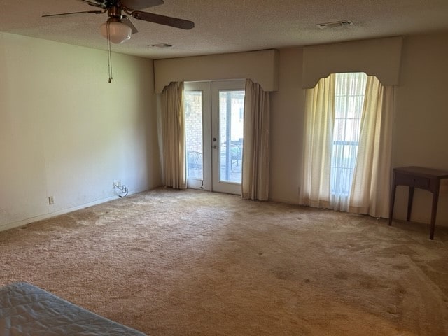 spare room featuring french doors, ceiling fan, carpet, and a textured ceiling