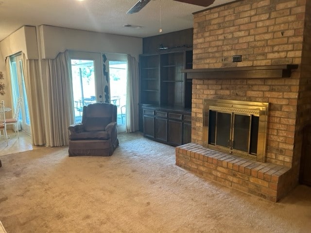 unfurnished living room featuring a textured ceiling, light colored carpet, ceiling fan, and a fireplace