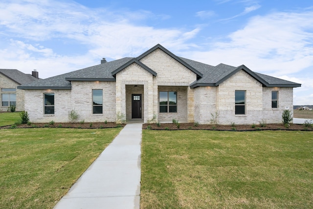 view of front facade with brick siding, roof with shingles, and a front yard