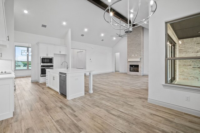 kitchen with white cabinets, open floor plan, light countertops, appliances with stainless steel finishes, and light wood finished floors