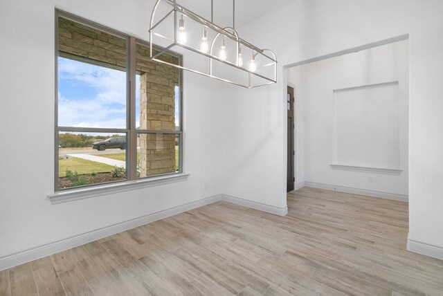 spare room with baseboards and wood finished floors