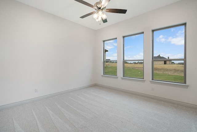 spare room with light carpet, ceiling fan, baseboards, and a wealth of natural light