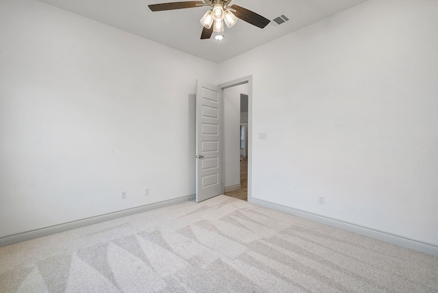 unfurnished room featuring baseboards, ceiling fan, visible vents, and light colored carpet