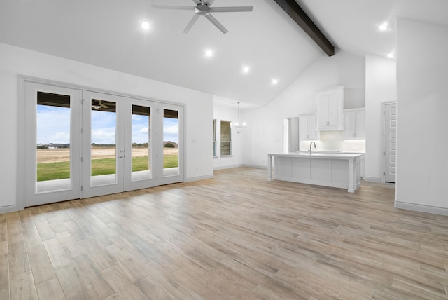 unfurnished living room featuring high vaulted ceiling, ceiling fan with notable chandelier, a sink, light wood-style floors, and beamed ceiling