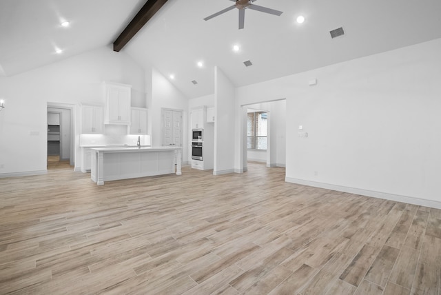 unfurnished living room featuring visible vents, light wood-style floors, a ceiling fan, high vaulted ceiling, and beamed ceiling