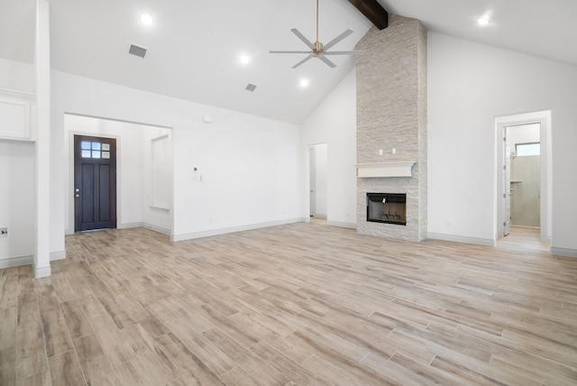 unfurnished living room with light wood finished floors, ceiling fan, beamed ceiling, a fireplace, and high vaulted ceiling