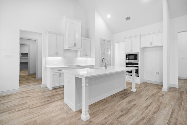 kitchen featuring white cabinets, a sink, stainless steel oven, and built in microwave