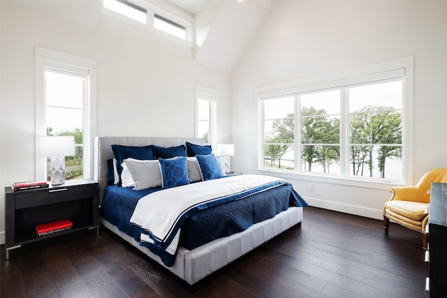 bedroom featuring dark wood-type flooring, multiple windows, and a high ceiling