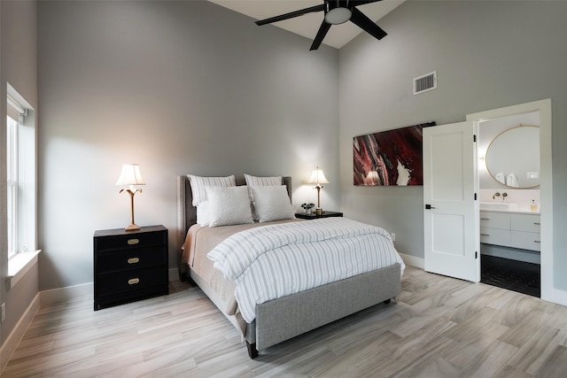 bedroom with connected bathroom, sink, high vaulted ceiling, light hardwood / wood-style flooring, and ceiling fan