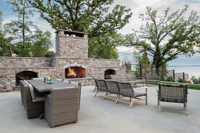 view of patio / terrace featuring a water view and an outdoor stone fireplace