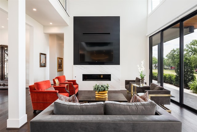 living room featuring decorative columns, dark hardwood / wood-style floors, a fireplace, and a towering ceiling