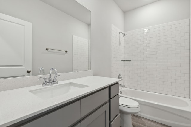 full bathroom featuring toilet, hardwood / wood-style floors, vanity, and tiled shower / bath combo