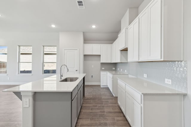 kitchen with white cabinetry, sink, decorative backsplash, dark hardwood / wood-style flooring, and a kitchen island with sink