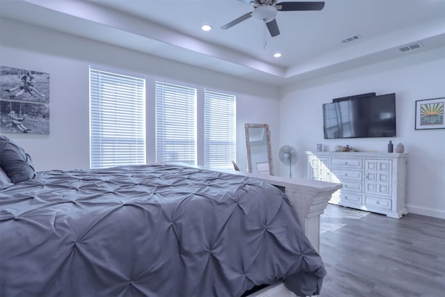 bedroom featuring a tray ceiling, ceiling fan, and dark wood-type flooring