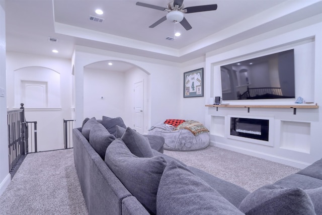 carpeted living room featuring a tray ceiling and ceiling fan