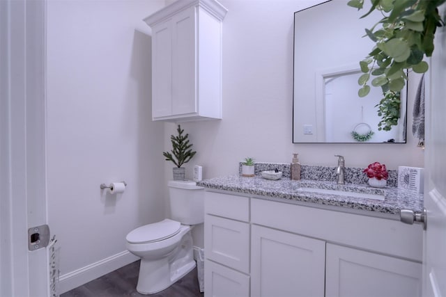 bathroom with hardwood / wood-style floors, vanity, and toilet