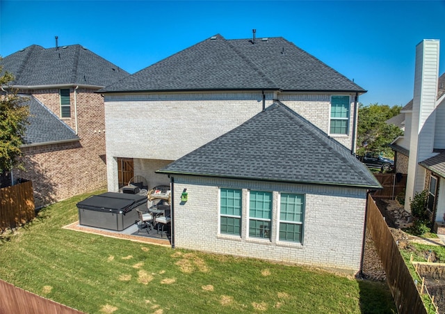 rear view of house with a yard, a hot tub, and a patio area