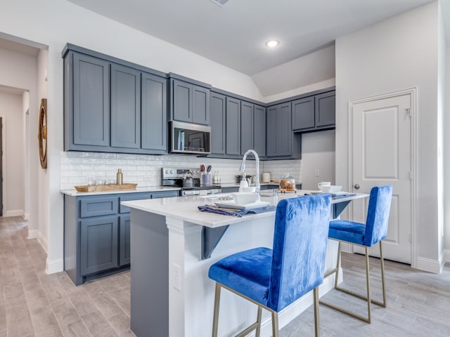 kitchen featuring an island with sink, a breakfast bar area, appliances with stainless steel finishes, and light hardwood / wood-style floors