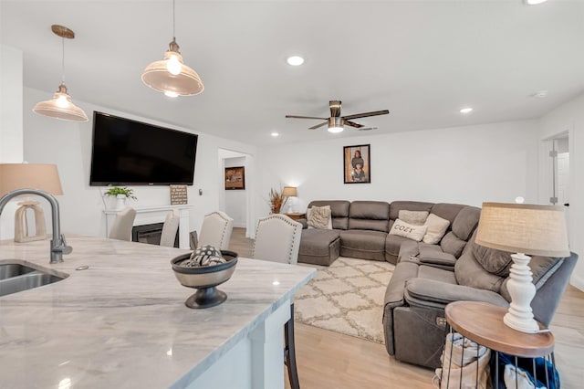 living room featuring a glass covered fireplace, a ceiling fan, recessed lighting, and light wood-style flooring