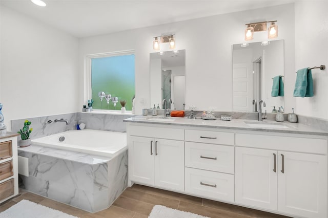 full bath featuring a sink, a shower with door, a garden tub, and double vanity