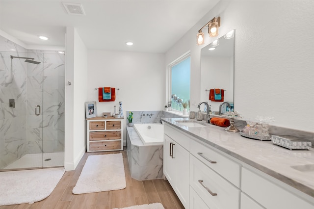 bathroom featuring vanity, wood-type flooring, and plus walk in shower