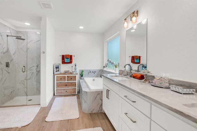 full bath with a garden tub, visible vents, vanity, wood finished floors, and a marble finish shower