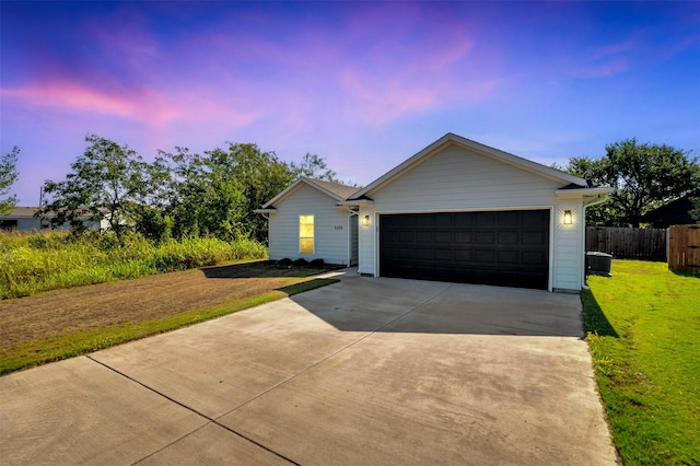 ranch-style house featuring an attached garage, a front lawn, fence, and driveway