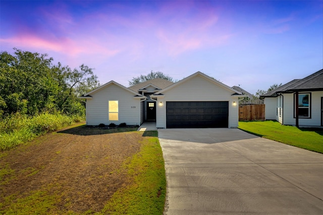 view of front of home featuring a garage, a front lawn, fence, and driveway