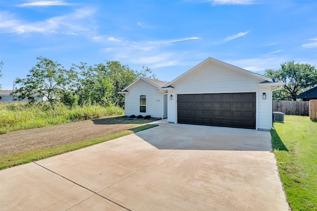 single story home featuring fence, an attached garage, driveway, and a front lawn