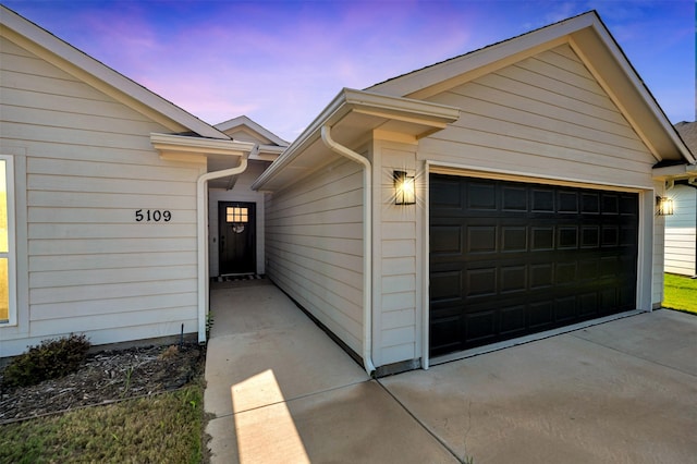 exterior entry at dusk featuring a garage