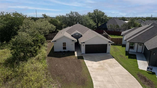 view of front of home with fence, an attached garage, driveway, and a front lawn