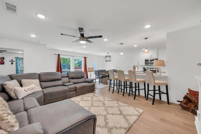 living room with light wood-type flooring and ceiling fan