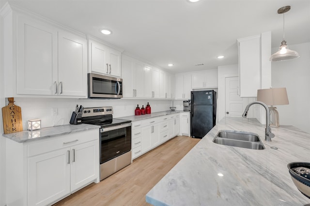 kitchen with hanging light fixtures, light hardwood / wood-style flooring, appliances with stainless steel finishes, white cabinetry, and sink