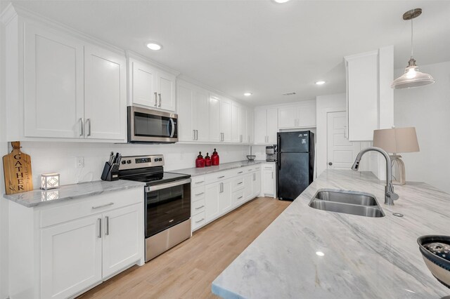kitchen with stainless steel appliances, a sink, light wood finished floors, and tasteful backsplash