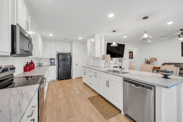 kitchen featuring white cabinetry, stainless steel appliances, sink, light stone countertops, and light hardwood / wood-style floors