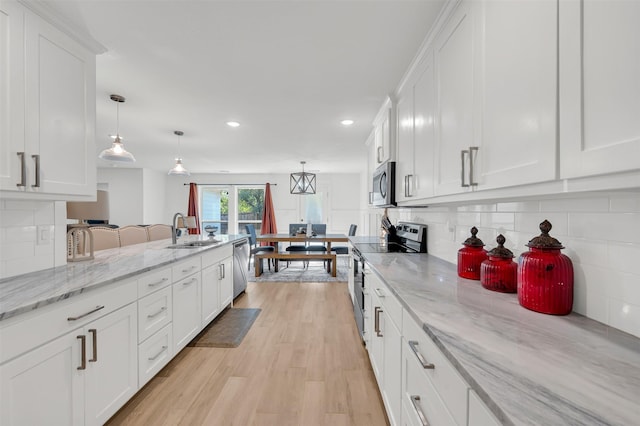kitchen with a sink, stainless steel appliances, recessed lighting, and white cabinetry