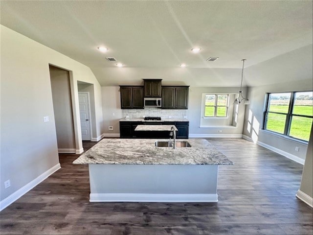 kitchen with dark hardwood / wood-style flooring, a center island with sink, lofted ceiling, and sink