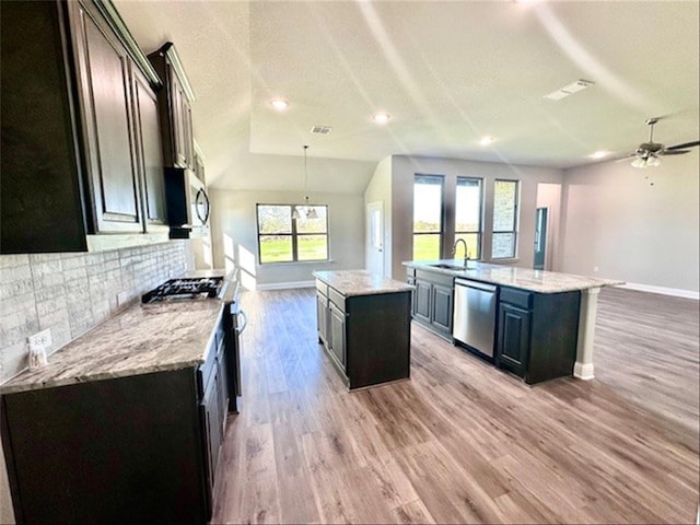 kitchen with a center island with sink, a wealth of natural light, lofted ceiling, and appliances with stainless steel finishes